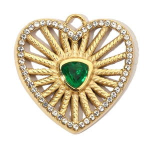 Macro shot of gold heart pendant with green triangular stone and sparkling crystal edges