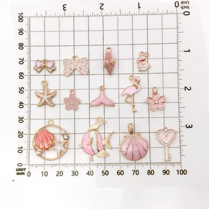 Pink enamel shell and animal alloy pendants measured on a metric scale for DIY jewelry