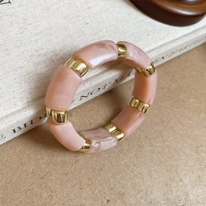 Detail of pink marble resin beads and golden spacers on an elastic bracelet