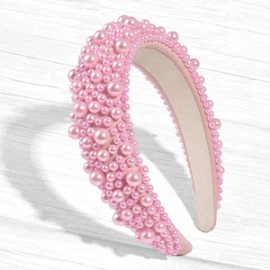 Close-up of pink padded headband with various sized faux pearls on white wooden table