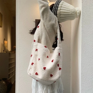 Detailed view of red heart embroidery on white plush tote bag with cozy sheepskin texture