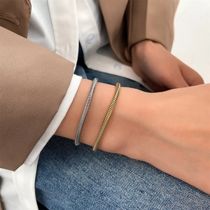 Detail of woven snake bone bracelets in gold and silver finish on a model's wrist