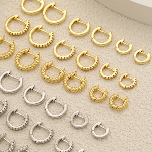 Makroaufnahme verschiedener Huggie-Ohrringe in Gold und Silber mit Zirkonia-Inlay