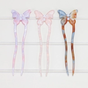 Detailed view of three acetate butterfly hair pins with pearl accents in assorted colors