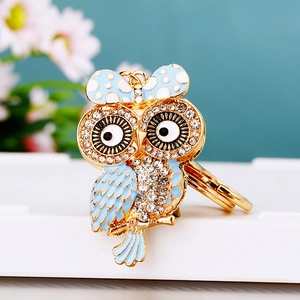 Macro shot of sparkling crystal owl keychain with blue enamel bow and gold metal finish