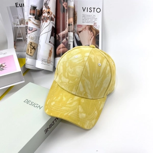 Dettaglio ravvicinato del cappellino tie-dye giallo appoggiato su libri di design di moda