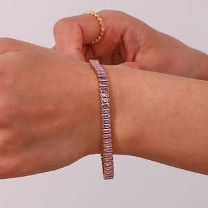 Detail of hand wearing a gold-plated bracelet and ring set with pink rectangular zircons
