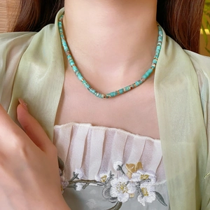 Close-up of a bohemian necklace with turquoise round beads on a model's neck