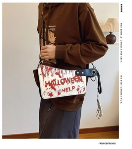 Detail of cleaver crossbody bag with blood splatters and skeleton hand charm accessory