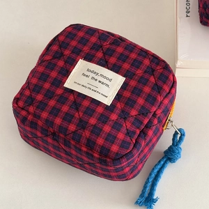 Red and blue plaid quilted storage pouch with woven label and blue zipper pull