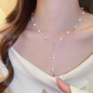 Detail of Y-shaped silver necklace with irregular pearls and metallic beads on model