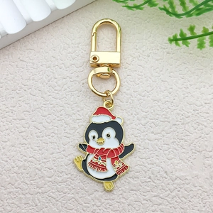 Detailed macro view of a Christmas penguin enamel keychain with festive red hat and scarf