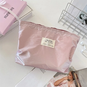 Detailed view of pink quilted vanity bag with glossy finish and woven brand label