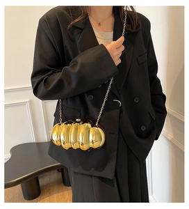 Detail of a golden marble-textured acrylic evening bag with a metallic chain strap
