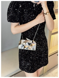 Close-up of a silver geometric acrylic clutch bag on a black sequin evening dress