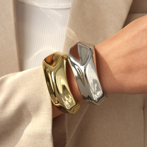 Close-up of gold and silver irregular liquid metal bracelets on a model's wrist