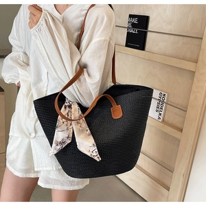 Detail of black woven tote bag with brown leather handles and a patterned decorative scarf
