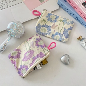 Flat lay of floral fabric makeup pouches with pink zipper pulls and cosmetic accessories