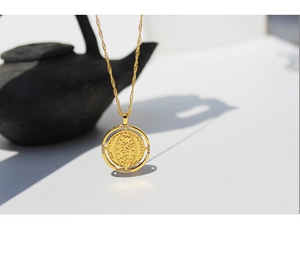 Detail of a rotating gold coin pendant necklace with zircon inlay on a white background