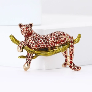 Macro detail of a vintage leopard brooch with red enamel spots on a golden branch