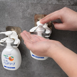 Close-up of wall-mounted soap dispenser holder being used on grey tiled bathroom wall