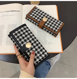 Detail of long houndstooth wallets with golden magnetic snap on a modern art book