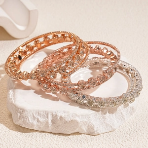 Macro shot of tiered zircon bracelets in rose gold and silver on white stone