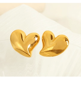 Vue macro de boucles d'oreilles cœur en or poli avec une finition métallique brillante