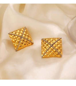Close-up of golden square earrings with quilted texture and silver bead cross detail