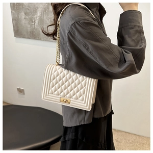 Detailed close-up of a white quilted shoulder bag with golden chain strap and buckle