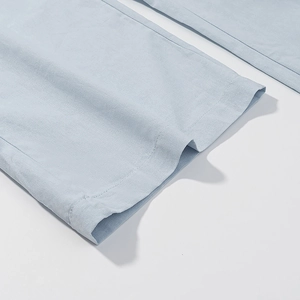 Detail view of light blue cotton linen trousers showing fabric texture and neat hem stitching