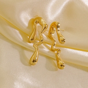 Macro shot of gold 14K stainless steel earrings with fluid molten liquid metal design