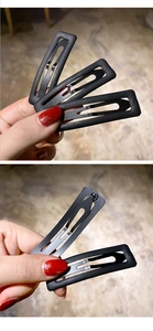 Detailed view of four matte black teardrop metal hair clips with smooth finish