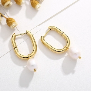 Detailed view of U-shaped gold earrings with elegant white oval pearl pendants