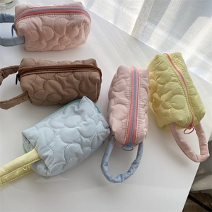 Detailed close-up of quilted floral cosmetic bags in five pastel colors with soft handles