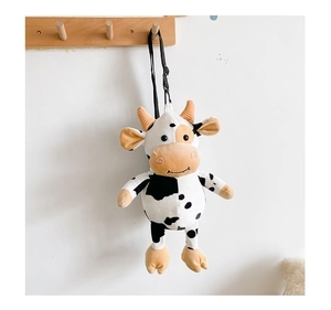 Detail of cute plush cow crossbody bag with black spots and soft fabric hanging on a hook