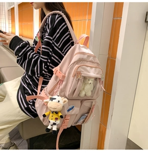 Zaino alla moda rosa multitasche con ciondoli di peluche visto di profilo sul modello