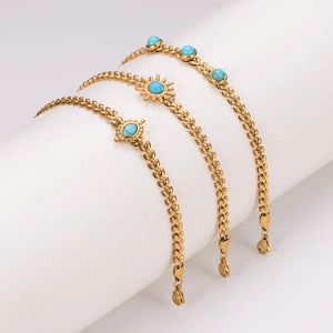 Gold leaf bracelet set with vintage sun charm and turquoise stones on a white stand