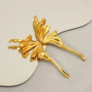 Detailed close-up of golden liquid metal butterfly earrings on a reflective mirror surface