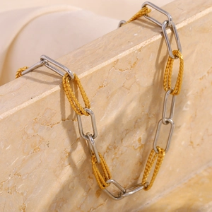 Detail of 18K gold and silver two-tone paperclip chain necklace on stone surface