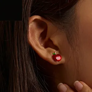Elegant S925 silver red apple stud earrings with glitter finish worn by a model