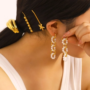 Boucles d'oreilles dorées avec perles et accessoires de cheveux portés par un modèle