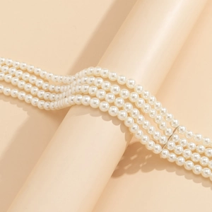 Close-up of four-layer faux pearl choker with silver spacers on a pink pedestal