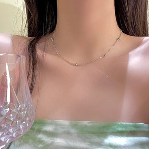 Close-up of a silver collar necklace featuring colorful zircon stones on a female model