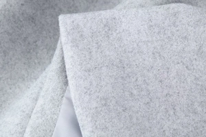 Détail de la texture du tissu en laine grise avec doublure lisse pour manteau femme