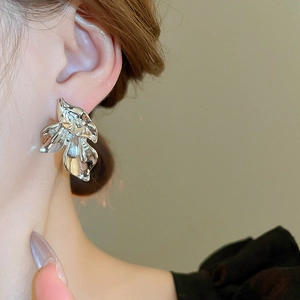 Close-up of abstract silver flower stud earring with polished mirror finish on model