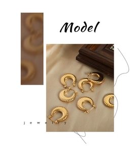 Detail of gold-plated titanium steel earrings with 3D radial texture on silk background