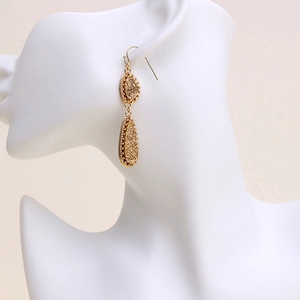 Elegant gold double teardrop earrings with textured finish on a white jewelry stand