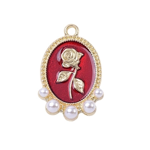 Golden oval charm with red enamel, rose pattern and five white pearls on white background