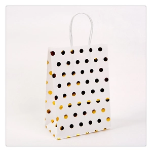 White kraft paper gift bag featuring gold foil polka dots and white twisted rope handles